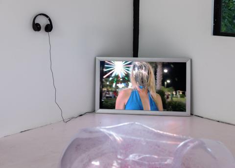 Performance mit Bildschirm in der Zimmerecke der eine Frau ohne Gesicht zeigt