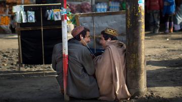zwei junge Männer teilen sich im Frühjahr 2014 an einer Kabuler Bushaltestelle einen Kopfhörer