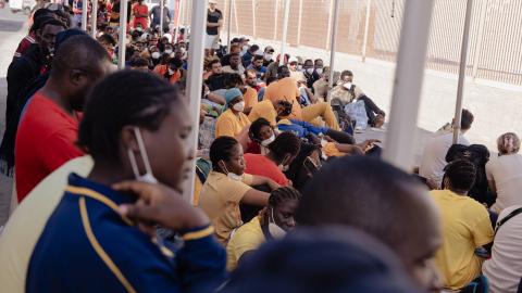 Migrant:innen warten am Hafen von Lampedusa auf die Fähre, die sie nach Sizilien bringt