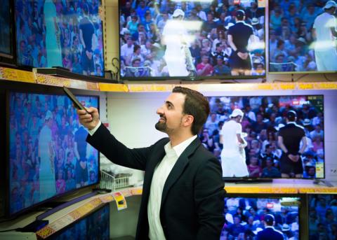 Olivier Kessler vor einer TV-Wand in einem Elektronikgeschäft