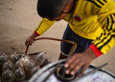 ein Pimpinero fülllt aus Venezuela geschmuggeltes Benzin in Pet-Flaschen ab