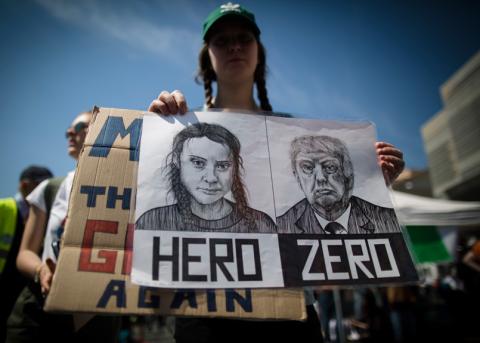 Eine junge Demonstrantin an einer Klimakundgebung hält ein Poster von Greta Thunberg und Donald Trump hoch.