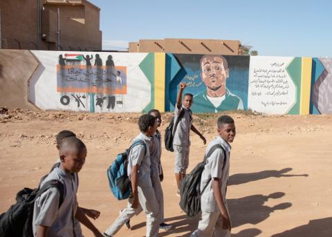 Jugendliche vor einem Wandgemälde mit dem Porträt von Mohammed Ibrahim