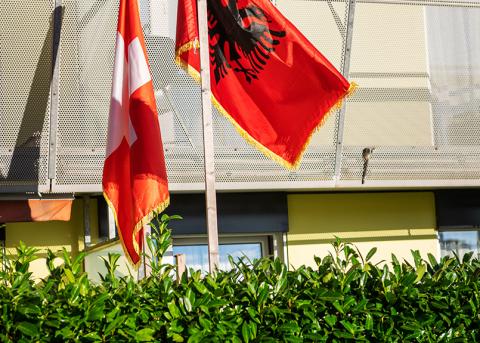 Eine albanische und schweizerische Flagge vor einem Haus