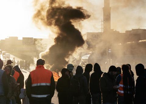 Blockade von Hafenarbeiter:innen mit brennenden Reifen vor dem Hafentor in Genua