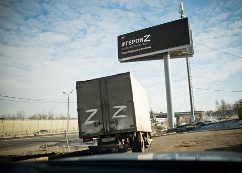 Propagandaplakat bei Moskau und Lastwagen davor, welche das Symbol Z tragen, welches das russische Regime für den Krieg gegen die Ukraine gewählt hat