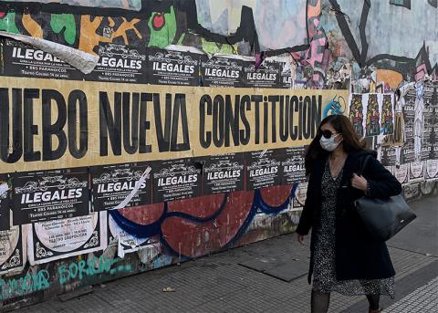 Eine Frau mit Hygienemaske läuft an Ja-Plakaten zur neuen Verfassung vorbei in den Strassen von Santiago 