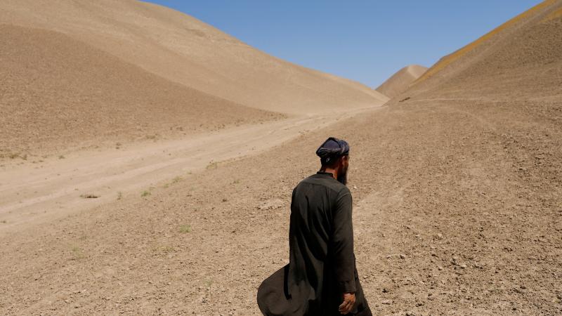 ein afghanischer Mann läuft auf steinigen Hügeln