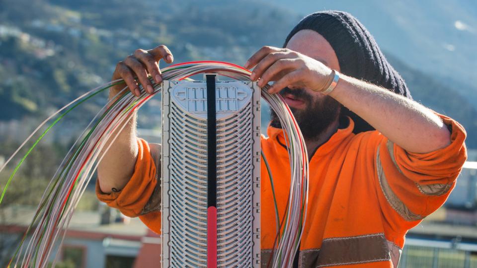 Arbeiter verlegt Glasfaserkabel in einem Verteilerkasten