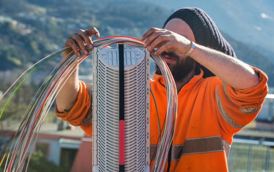Arbeiter verlegt Glasfaserkabel in einem Verteilerkasten