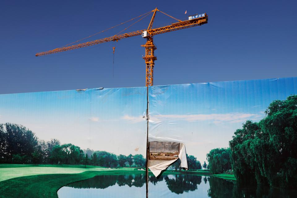 Absperrwand vor einer Baustelle für eine luxuriöse Wohnanlage, im Hintergrund ein Baukran