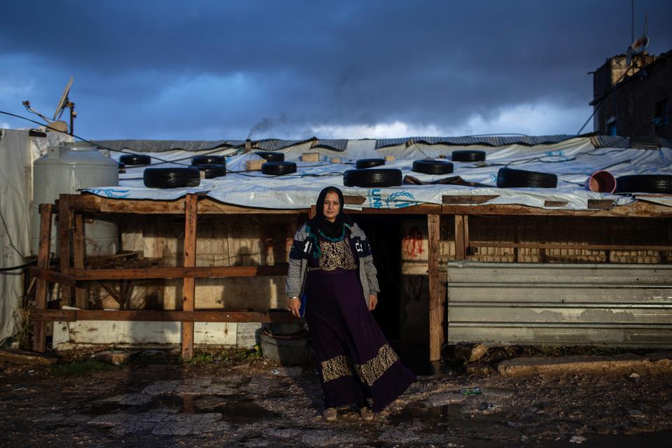 Amsche, die Leiterin des Lagers für Geflüchtete, steht vor improvisierten Behausungen des Lagers, welches in der libanesischen Bekaa-Hochebene liegt