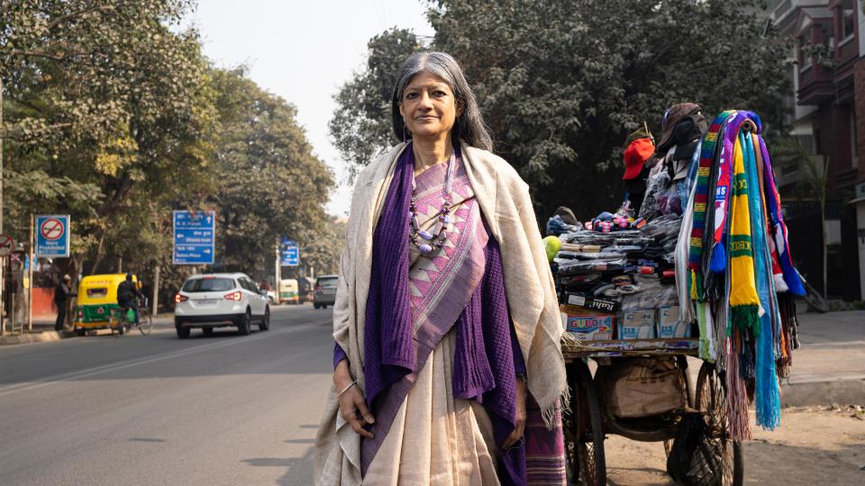 Portraitbild: Jayati Ghosh steht bei einem Verkaufsstand für Kleider neben einer Strasse