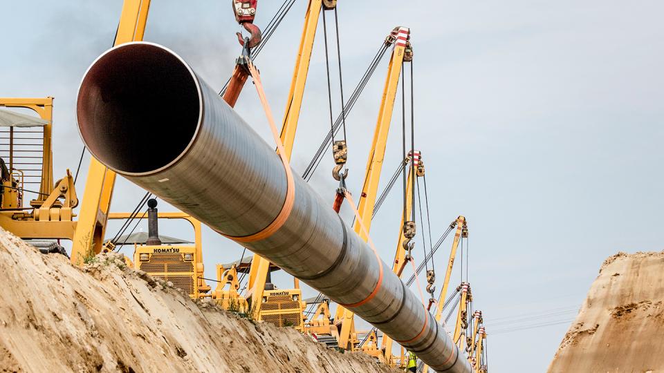 Kräne hieven Leitungsröhren in einen Graben für die Eugal-Pipeline in Ostdeutschland