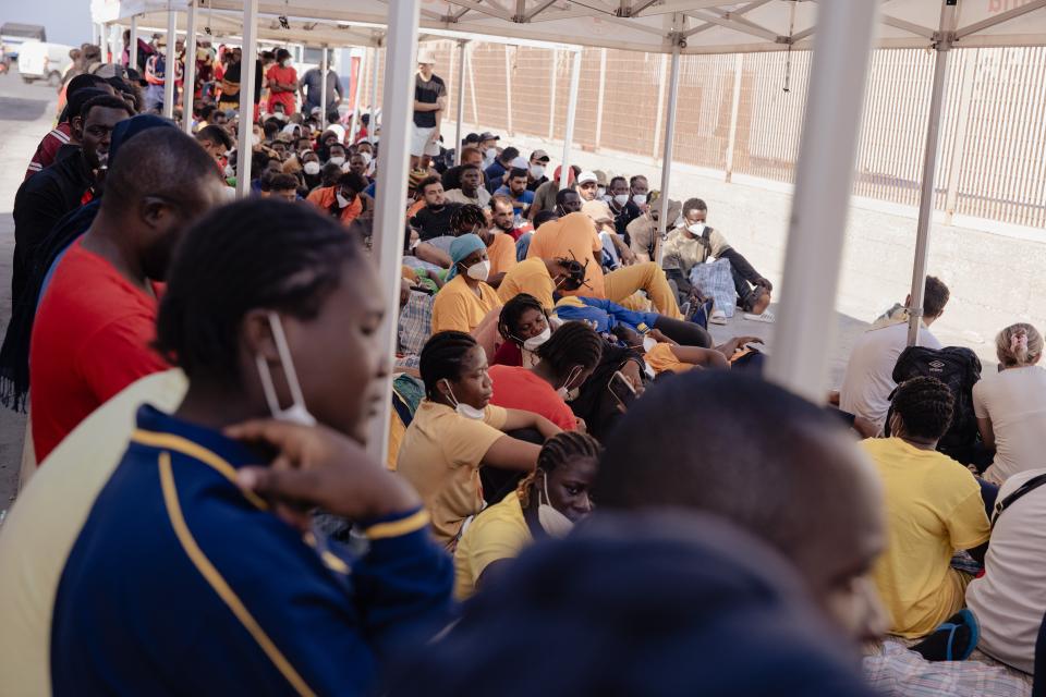 Migrant:innen warten am Hafen von Lampedusa auf die Fähre, die sie nach Sizilien bringt