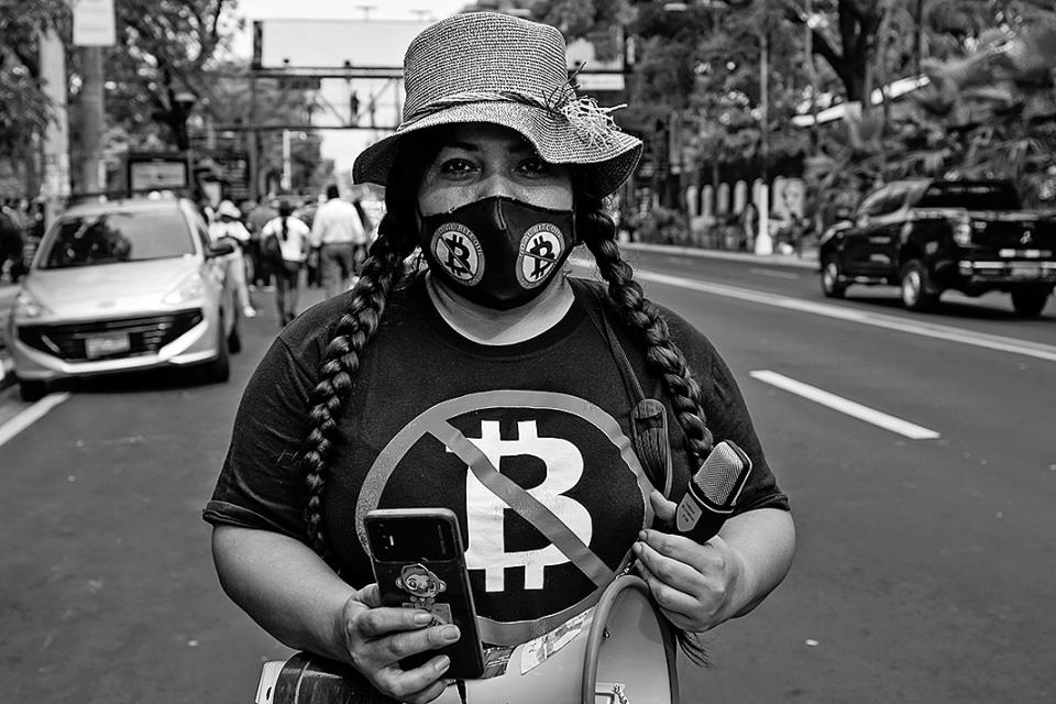 eine Frau auf der Strasse mit Bitcoin-T-Shirt und einer Gesichtsmaske mit Bitcoins-Aufdruck