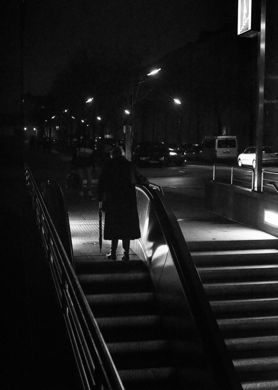 eine Person benützt nachts eine Rolltreppe