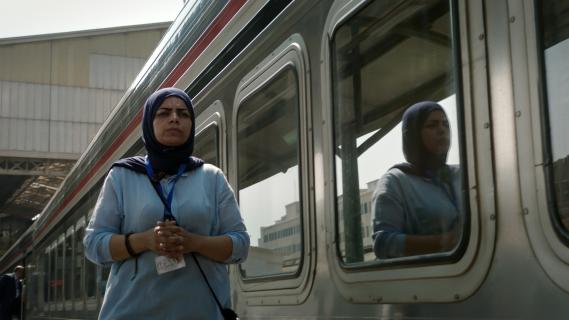 Filmstill aus Filmstill aus «Mahatah – Side Stories from Main Stations»: Frau mit Kopftuch neben einem Zugwagon