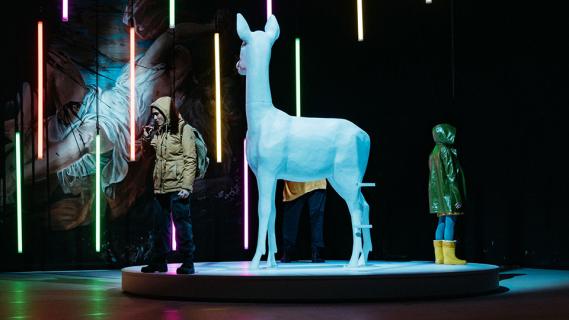 Foto des Theaterstücks «Antigone in Butscha»: 2 Personen in Winterkleidung stehen neben der Skulptur eines Rehs